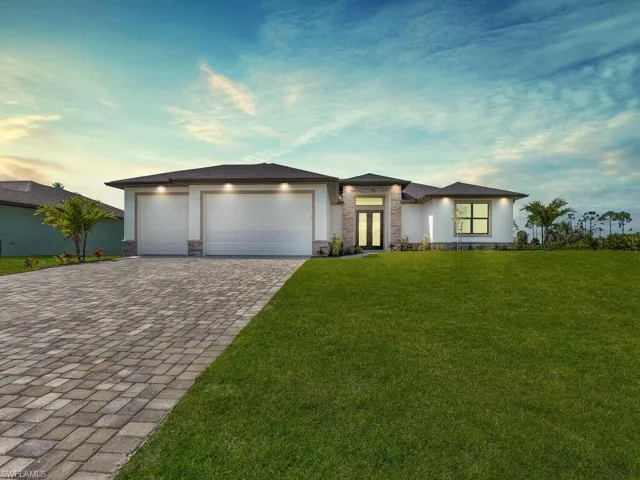 Prairie-style house featuring stone siding, french doors, decorative driveway, and stucco siding