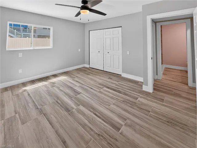 Spacious room featuring wood-finish flooring, a contemporary ceiling fan, and ample natural light from the window