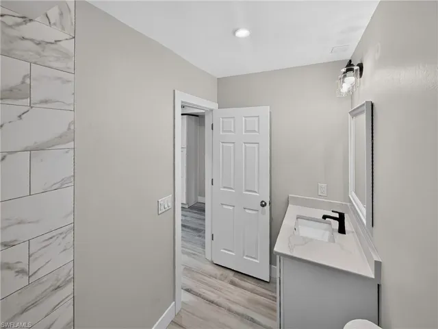 Contemporary bathroom featuring a white vanity with an integrated rectangular sink, a matte black faucet, and a wall-mounted mirror