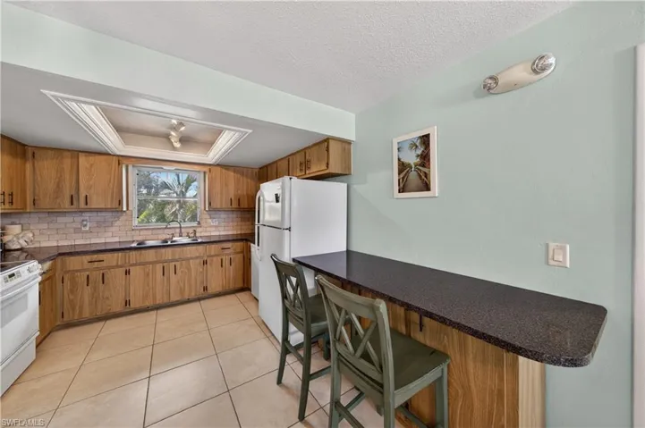 Kitchen featuring wood-finish cabinetry, dark countertops, and a white subway tile backsplash
