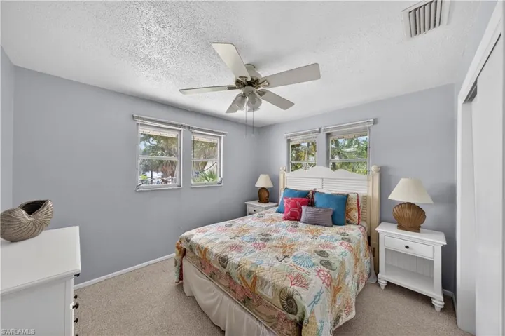 Bedroom featuring a ceiling fan, two windows with horizontal blinds, and a built-in closet with white bifold doors