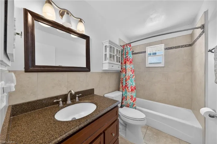 Bathroom featuring a wood-finish vanity with an undermount sink and speckled stone countertop