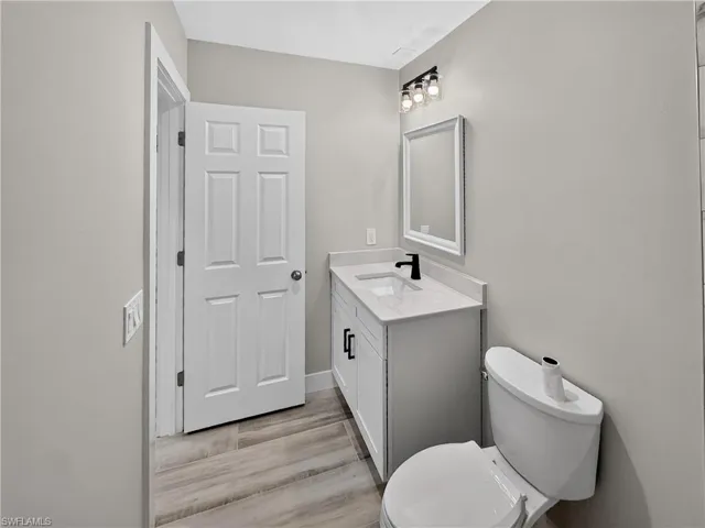 Bathroom featuring a white vanity with a light-toned countertop, black faucet, and frameless mirror