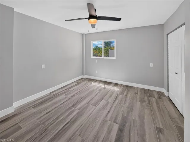 Spacious room featuring wood-finish tile flooring, neutral gray walls, and white baseboards