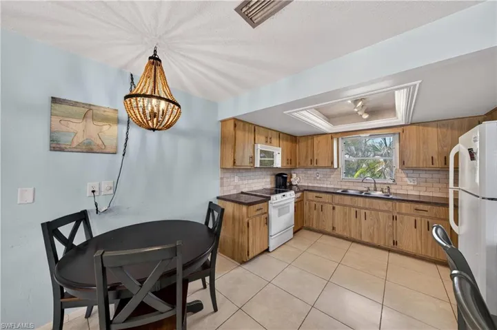 Kitchen featuring light wood cabinetry, white subway tile backsplash, and dark countertops