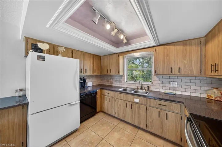 Kitchen featuring wood-finish cabinetry, dark countertops, and a white subway tile backsplash