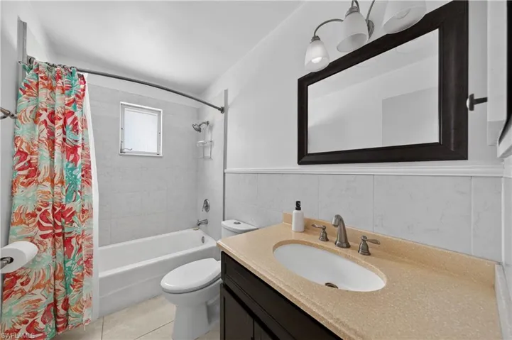 Bathroom featuring a vanity with an integrated sink and light-colored countertop, a dark wood-framed mirror, and a three-light vanity fixture