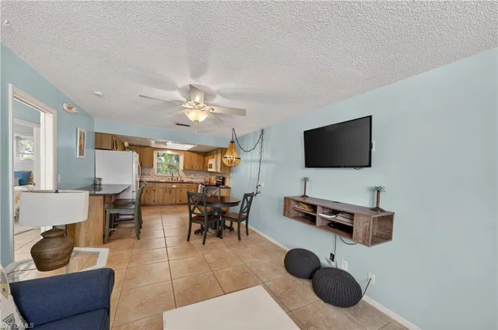 Open-concept kitchen and dining area featuring ceramic tile flooring, wood cabinetry, and a ceiling fan