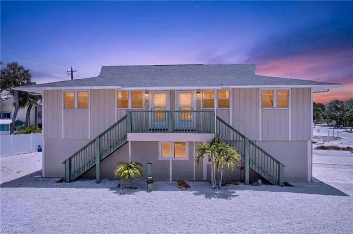 Elevated coastal structure featuring a gray shingle roof and light-toned vertical siding