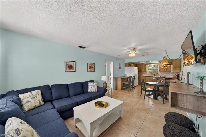 Living area featuring tile flooring, light blue wall paint, and a ceiling fan