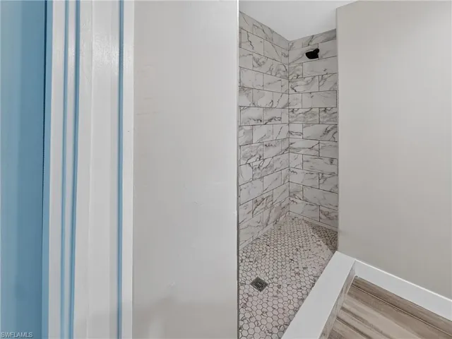 Walk-in shower featuring subway tile walls, a hexagonal mosaic tile floor, and a dark-finish shower head