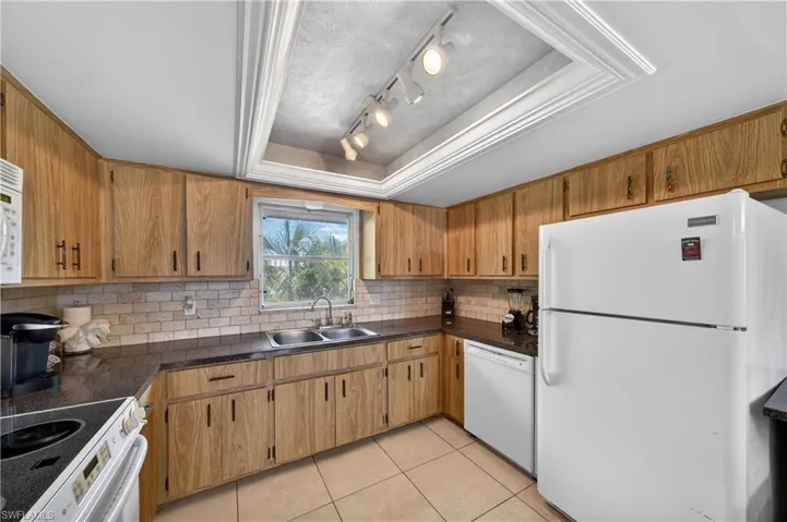 Kitchen featuring wood-finish cabinetry, dark countertops, and a subway tile backsplash