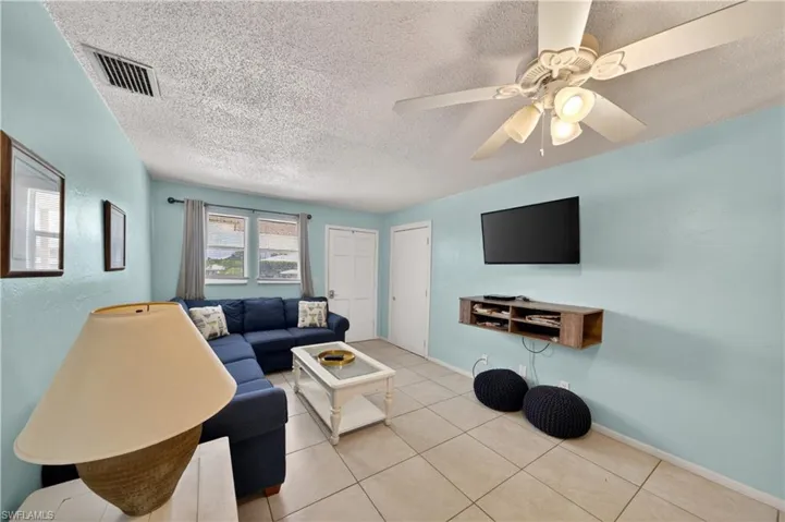 Living area featuring light-toned tile flooring and pale blue wall finishes