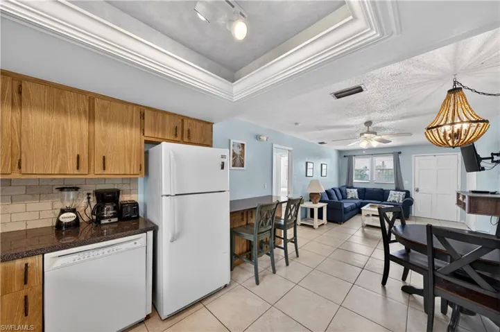 Open-concept living area featuring an eat-in kitchen with wood cabinetry and tile flooring