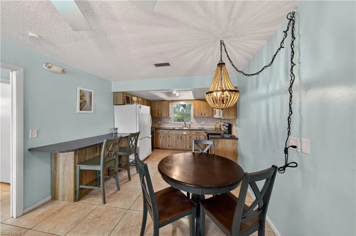 Open-concept kitchen featuring wood-finish cabinetry, tile flooring, and a subway tile backsplash