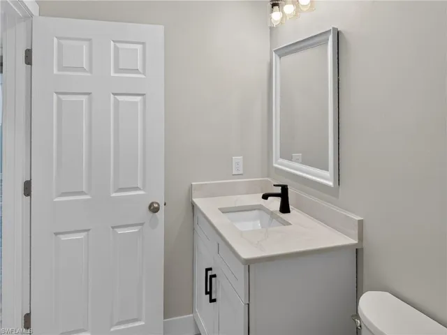 Bathroom vanity featuring a light-toned countertop, integrated sink, and matte black faucet