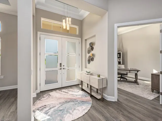 Foyer entrance with french doors, crown molding, and dark wood-style flooring