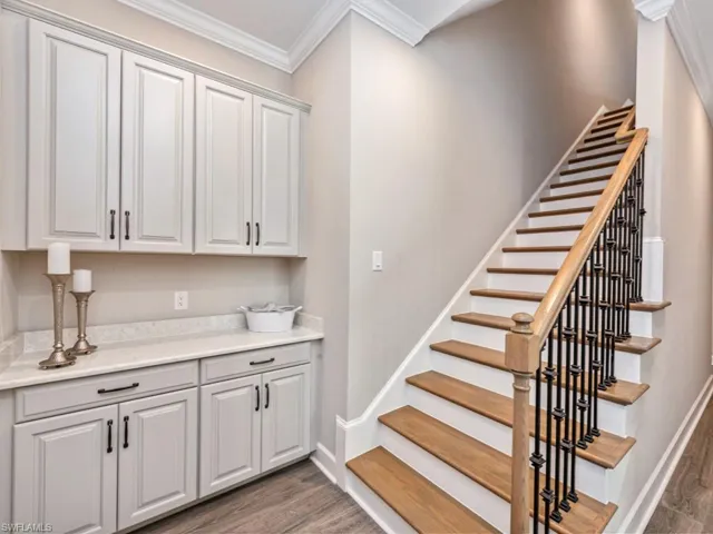 Stairs featuring wood finished floors and ornamental molding