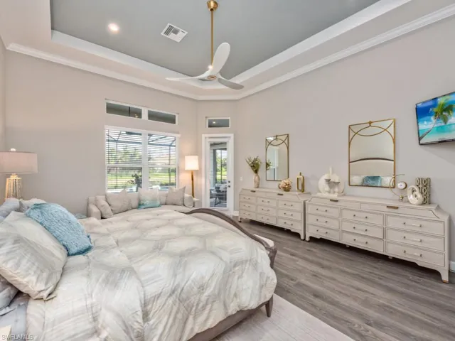 Bedroom featuring wood finished floors, a ceiling fan, crown molding, access to outside, and a tray ceiling