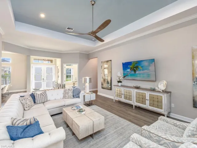 Living area with a tray ceiling, a ceiling fan, wood finished floors, french doors, and ornamental molding
