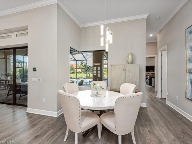 Dining room with a sunroom, crown molding, dark wood finished floors, and healthy amount of natural light