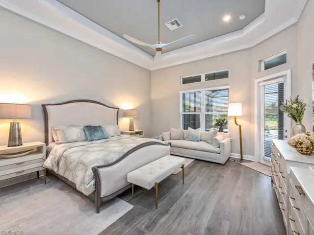 Bedroom featuring dark wood-style floors, a ceiling fan, a tray ceiling, access to exterior, and a towering ceiling