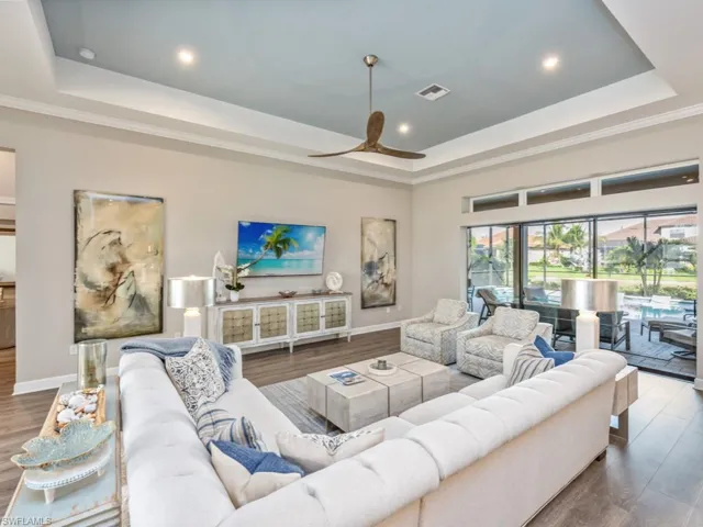 Living area featuring a raised ceiling, wood finished floors, ceiling fan, and recessed lighting
