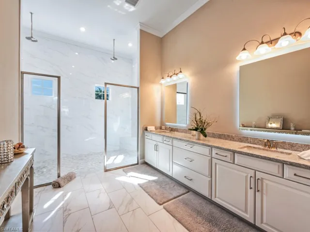 Bathroom featuring light marble finish flooring, double vanity, ornamental molding, recessed lighting, and a marble finish shower