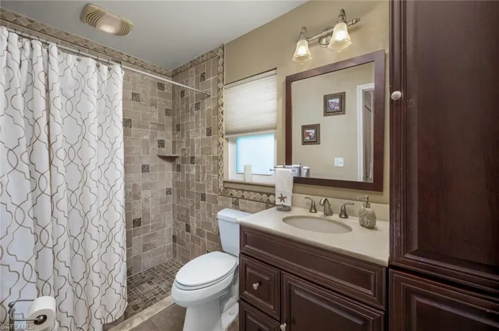 Ensuite bathroom with walk in shower, tiled flooring and linen cabinet.