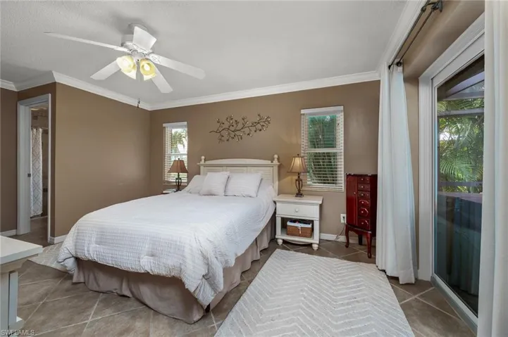 Primary Bedroom with tiled flooring, crown molding and walk in closet.