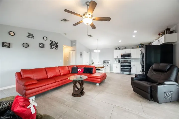Living room with lofted ceiling, a ceiling fan, light tile patterned floors, and recessed lighting