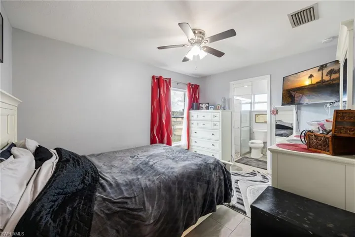 Bedroom with ceiling fan, connected bathroom, and tile patterned floors