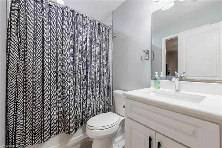 Bathroom with vanity, a textured wall, and shower / bath combo with shower curtain