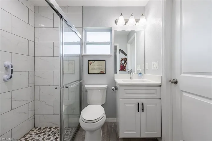 Full bath with a stall shower, vanity, and a textured wall