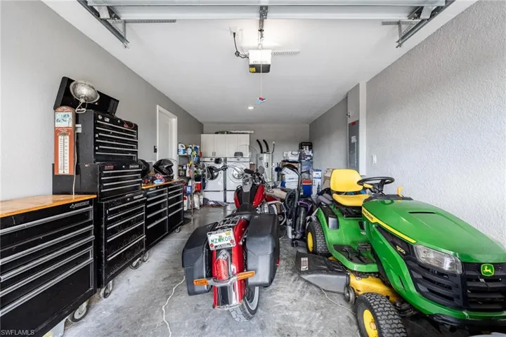 Garage featuring a textured wall, washer and dryer, electric panel, and a garage door opener