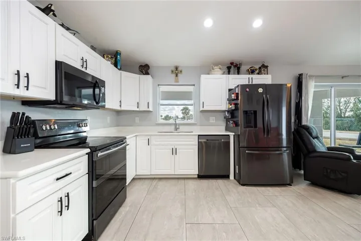 Kitchen with appliances with stainless steel finishes, white cabinetry, recessed lighting, and open floor plan