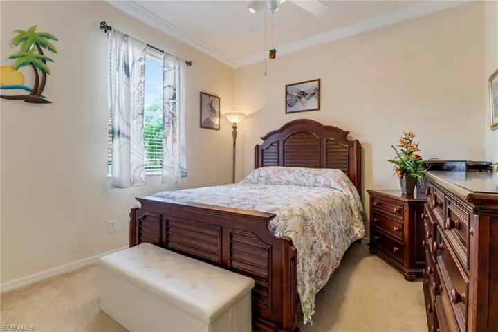 Bedroom with light carpet, ornamental molding, and a ceiling fan
