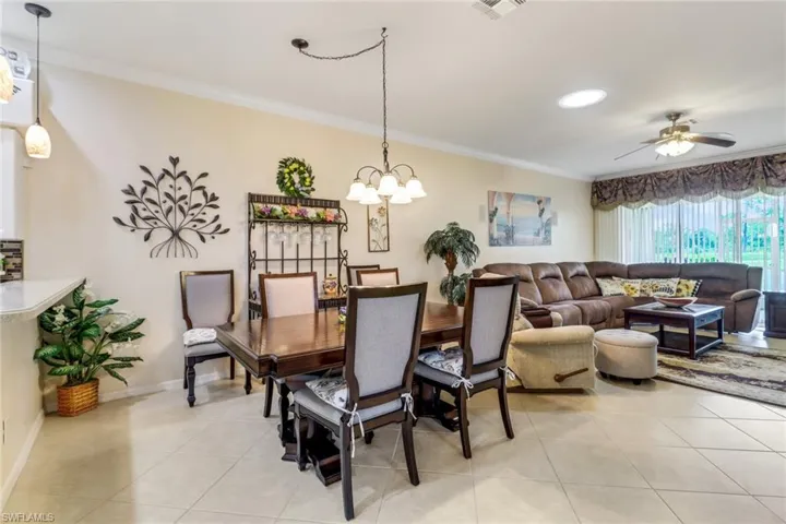 Dining room with ornamental molding, light tile patterned flooring, ceiling fan, and a chandelier