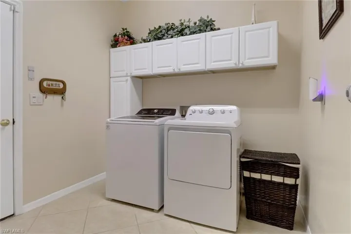 Washroom featuring cabinet space, washing machine and dryer, and light tile patterned floors