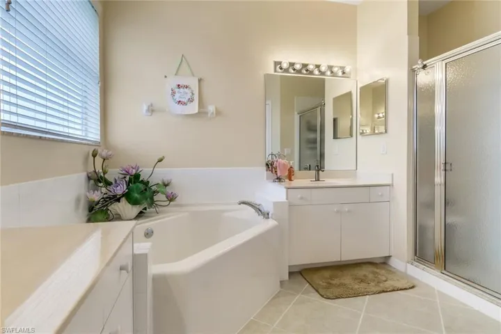 Bathroom with vanity, a shower stall, a bath, and tile patterned floors