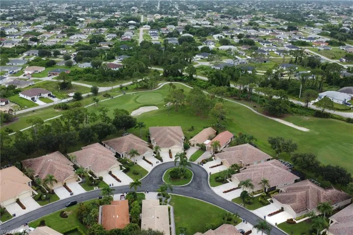 Aerial view of property and surrounding area featuring nearby suburban area and a golf course