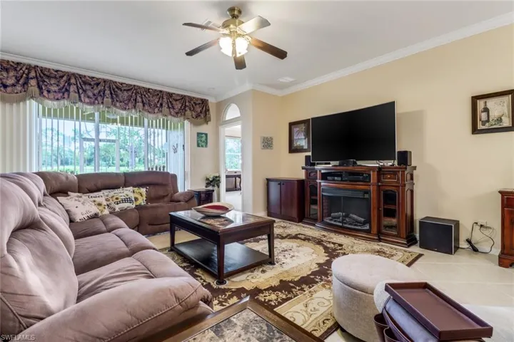 Tiled living area featuring ceiling fan and crown molding