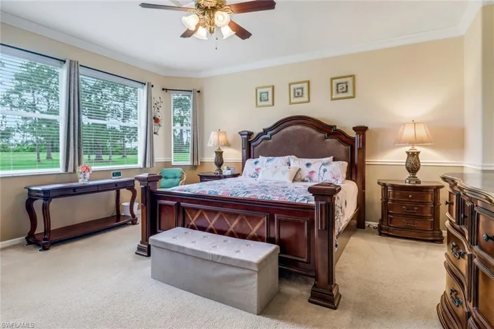 Carpeted bedroom with ornamental molding and a ceiling fan