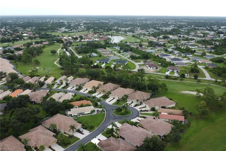 Aerial view of property's location featuring nearby suburban area, a golf course, and a large body of water
