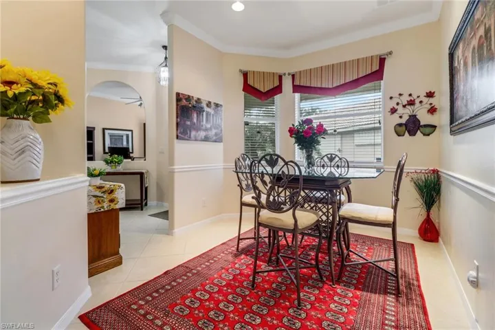 Dining area featuring light tile patterned flooring, crown molding, and arched walkways