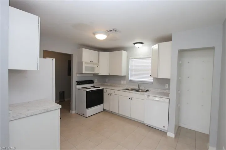 Kitchen with white cabinetry, sink, and white appliances