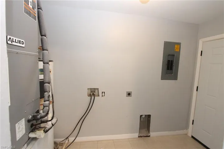 Clothes washing area with light tile patterned floors, hookup for a washing machine, electric panel, heating unit, and hookup for an electric dryer
