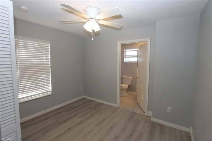 Unfurnished bedroom with ceiling fan, connected bathroom, and light hardwood / wood-style flooring