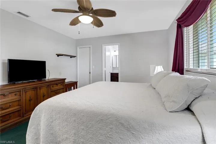 Carpeted bedroom featuring ceiling fan and ensuite bathroom