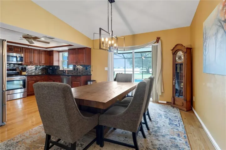 Dining room featuring ceiling fan with notable chandelier, light hardwood / wood-style flooring, sink, and a healthy amount of sunlight
